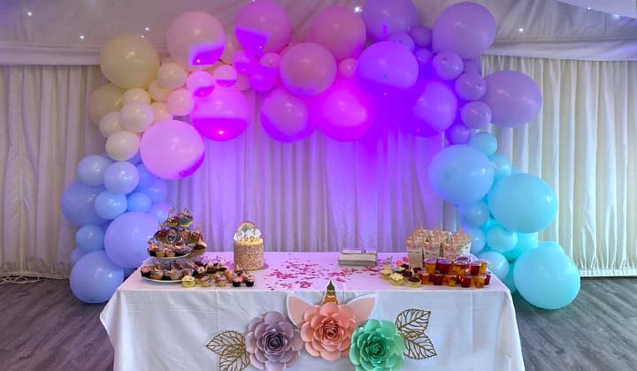 A milestone birthday party with a styled balloon arch and dessert table