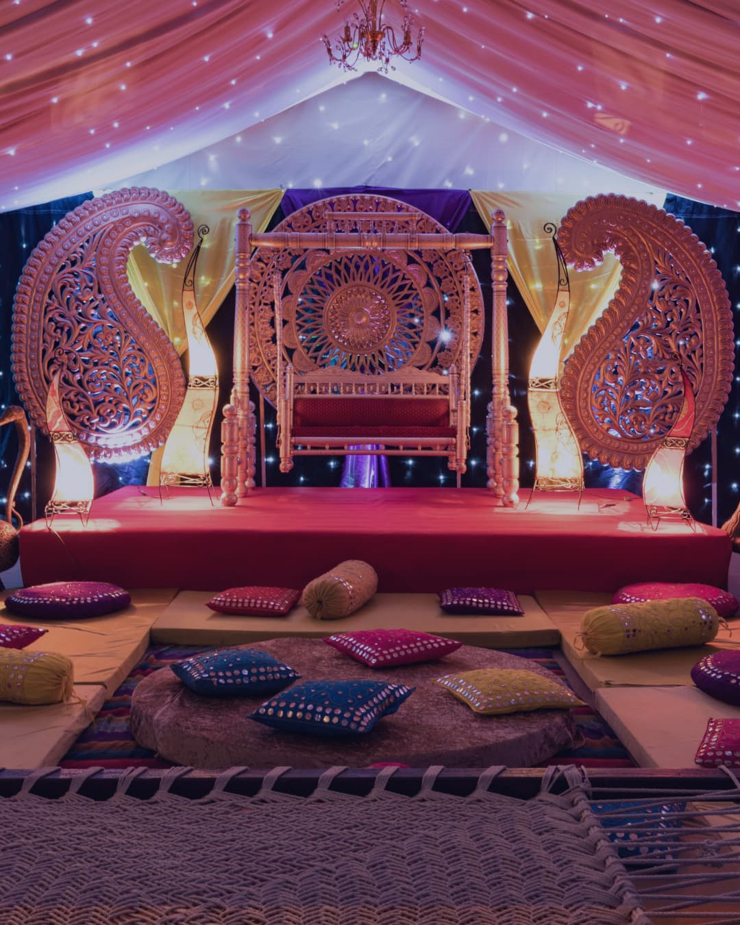 An ornate mandap staged in the marquee with floor cushions and rugs